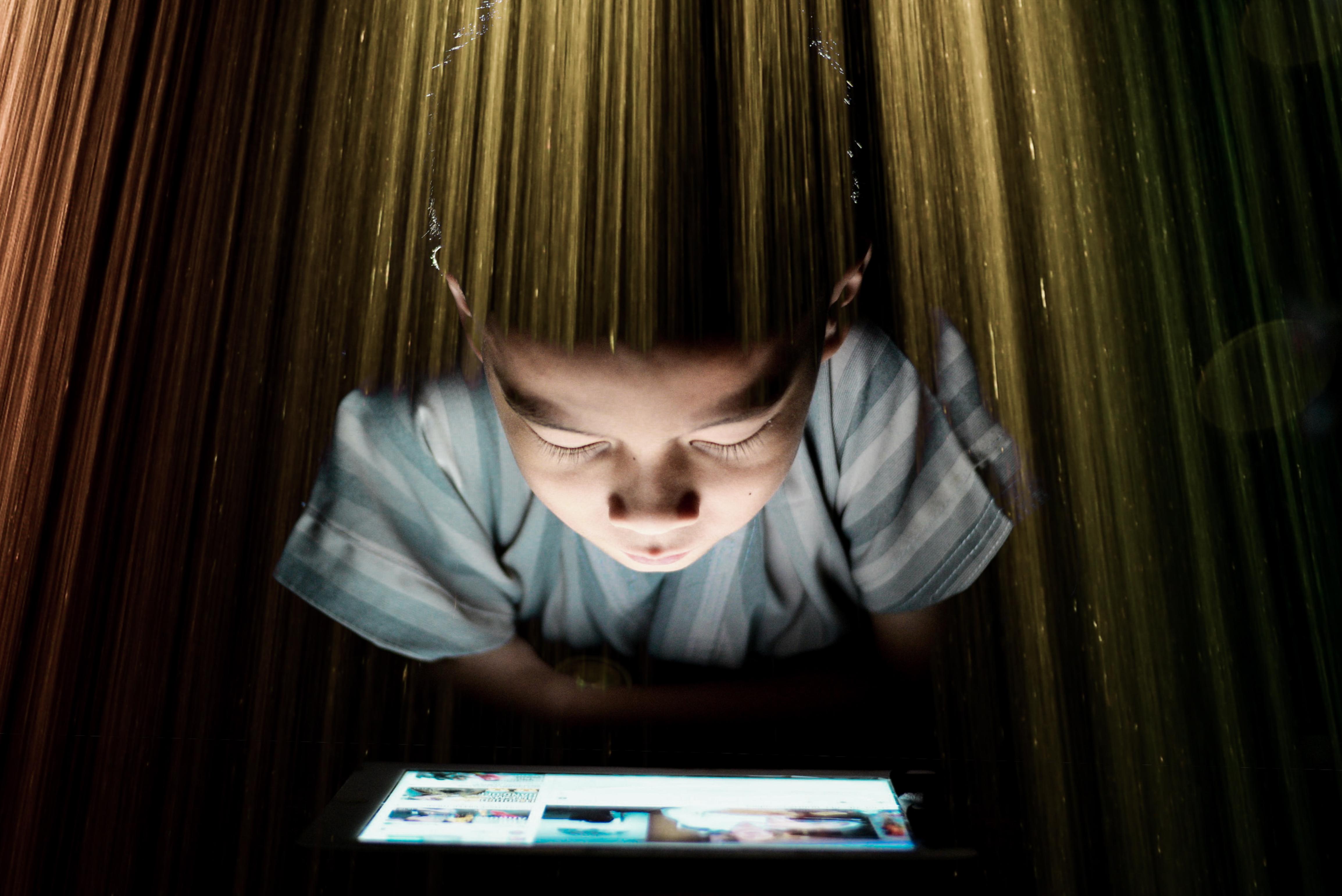 double-exposure-image-boy-using-digital-tablet-curtain