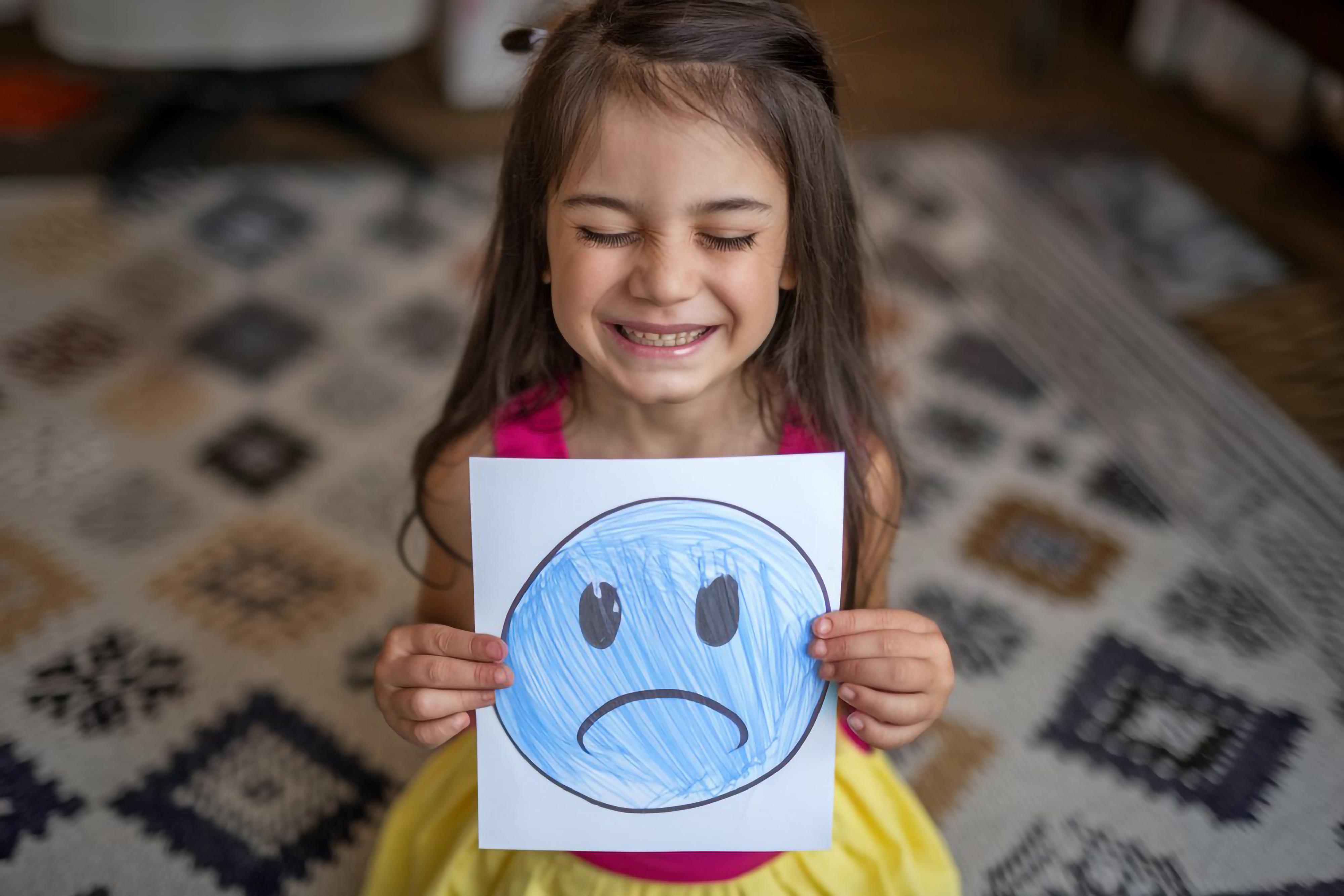 girl-holding-drawing-sad-face-with-sad-face-it
